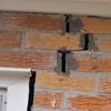 A brick wall displaying stair-step cracks and messy tuckpointing on a Beaufort home