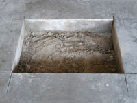 Creating the hole in the garage slab floor during the wall anchor installation in Swainsboro.