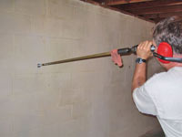 Drilling the hole in the foundation wall for street creep repairs in Guyton