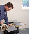 installing a waterproof vapor barrier on a basement floor to prepare for basement carpeting in a Beaufort home